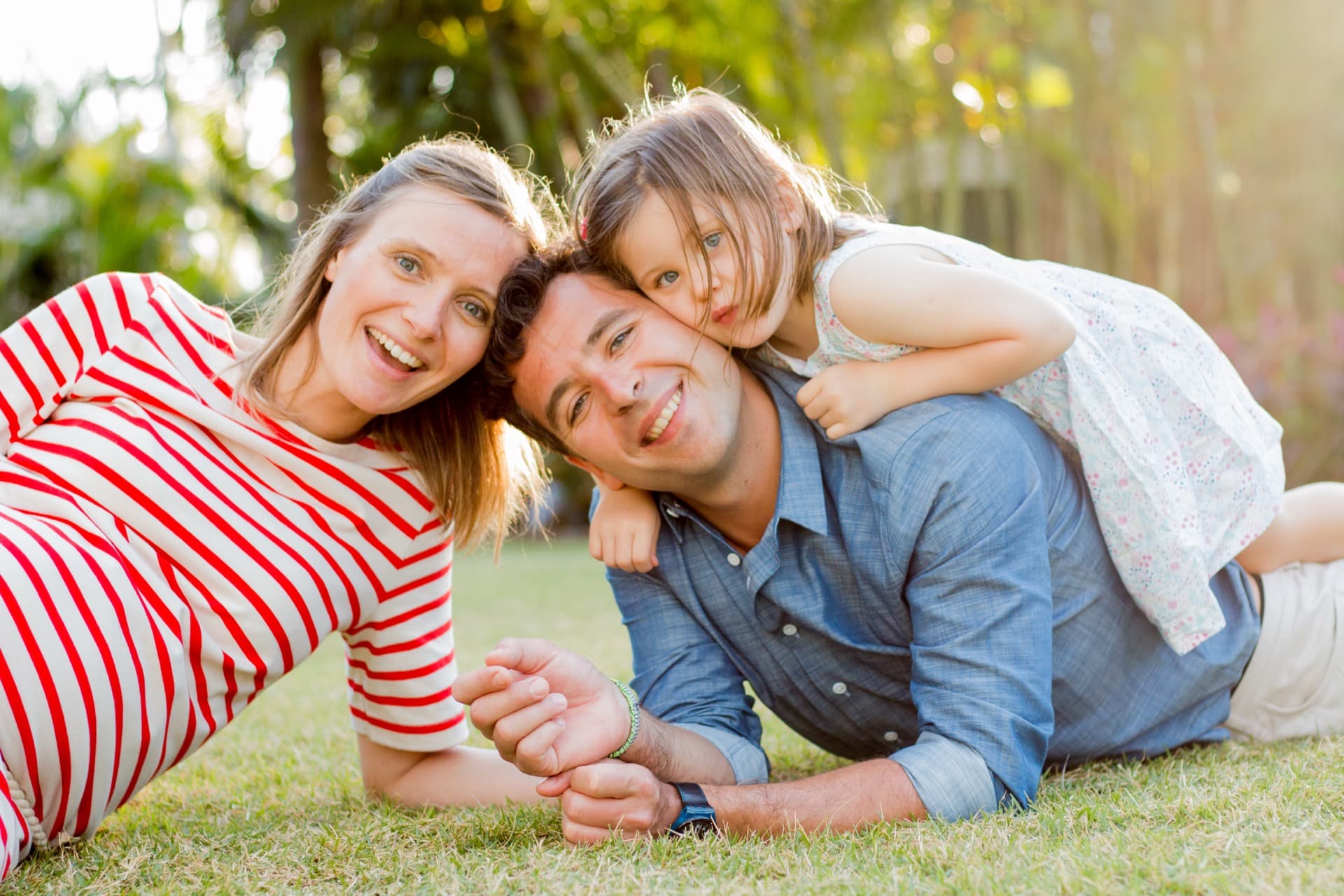 Family of three laughing together on the grass